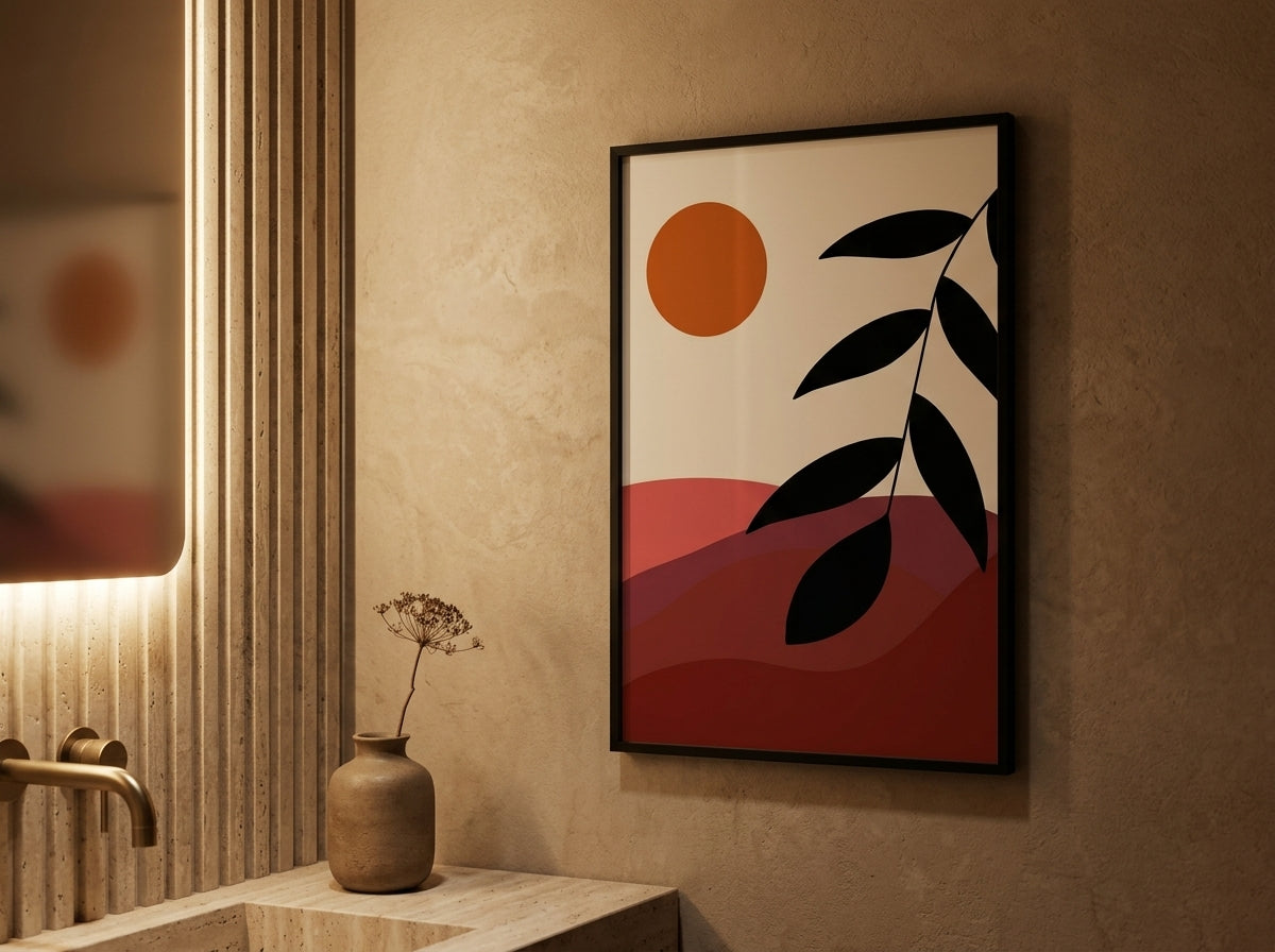 Single abstract sun and landscape art print in terracotta and burnt orange, black frame, above a warm bathroom vanity by VYLOIRE